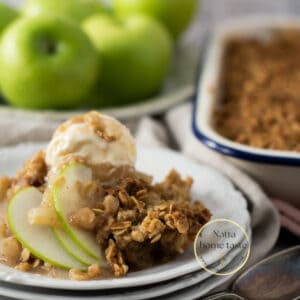 crumble de manzana servido en un plato de blanco con una bola de helado de vainilla