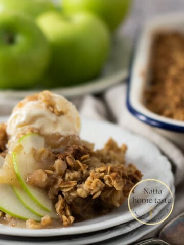 crumble de manzana servido en un plato de blanco con una bola de helado de vainilla