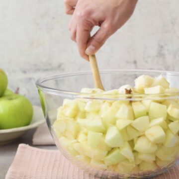 Manzanas verdes cortadas en cubos en un bol transparente.