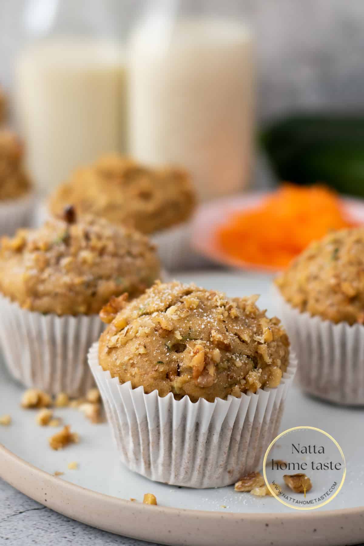 Muffins de zucchini y zanahoria con nueces al rededor servidos en un plato redondo