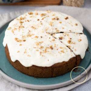 Torta de zanahoria redonda con glaseado de yogur griego y nueces servida en un plato redondo