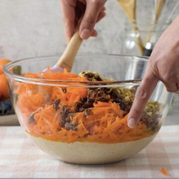 Tazón transparente con una mezcla de harina de avena, zanahorias ralladas, uvas pasas y nueces