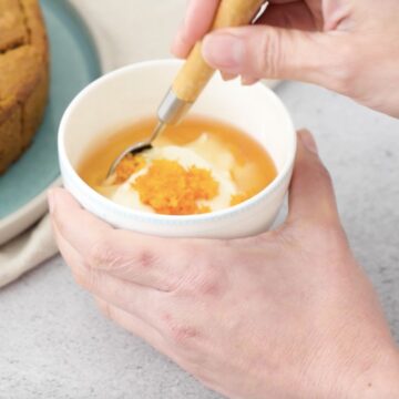 Taza blanca pequeña con yogur griego, agave y ralladura de naranja