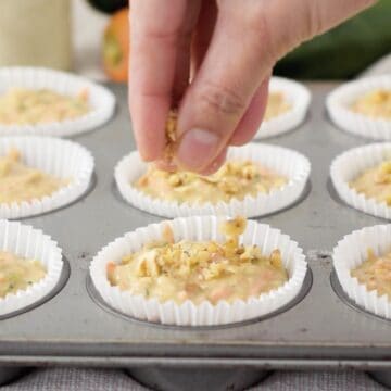 molde de muffins con capacillos de papel con mezcla de muffins y nueces por encima.