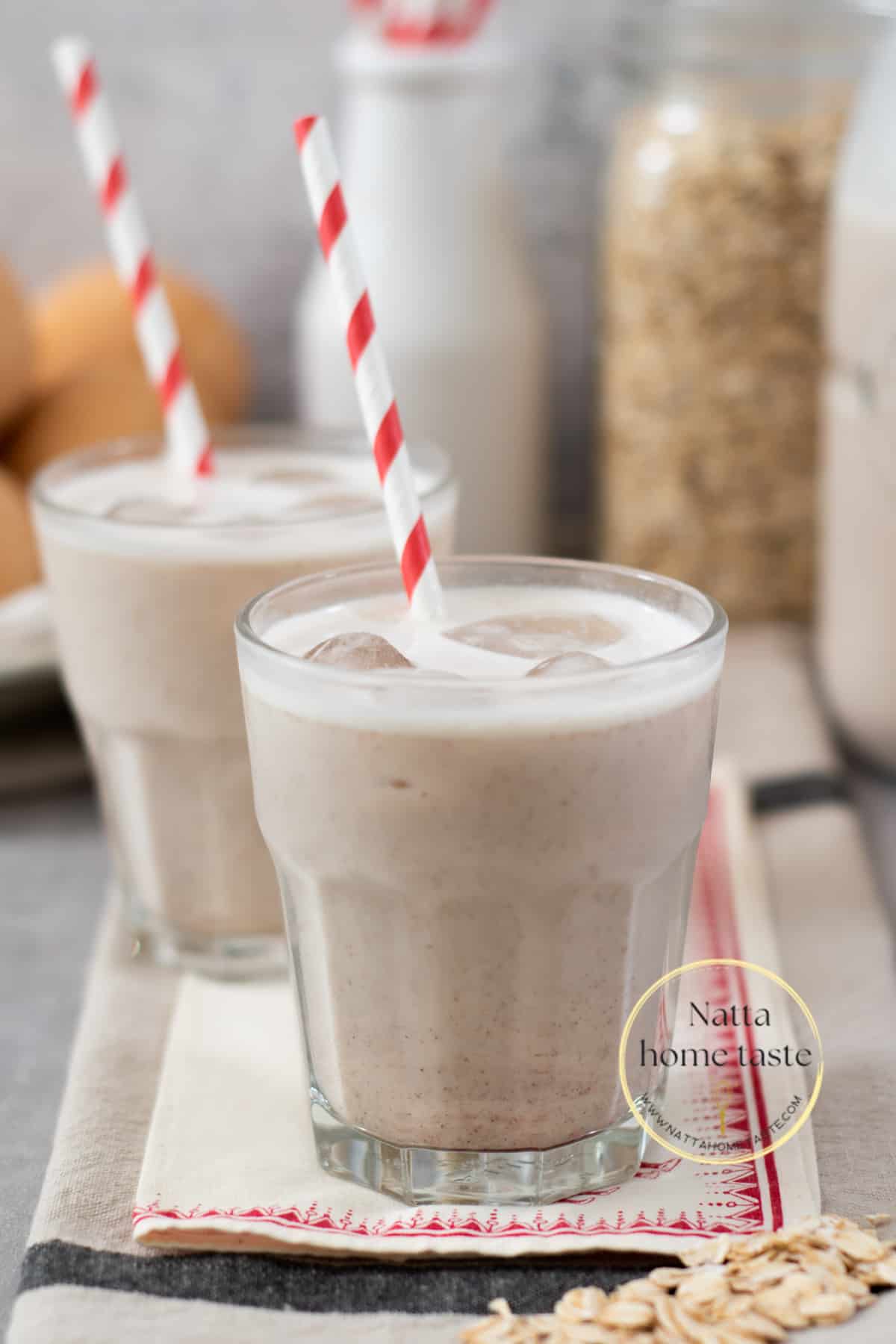 dos vasos de avena fría con hielo servidas con pitillos de papel sobre una mesa