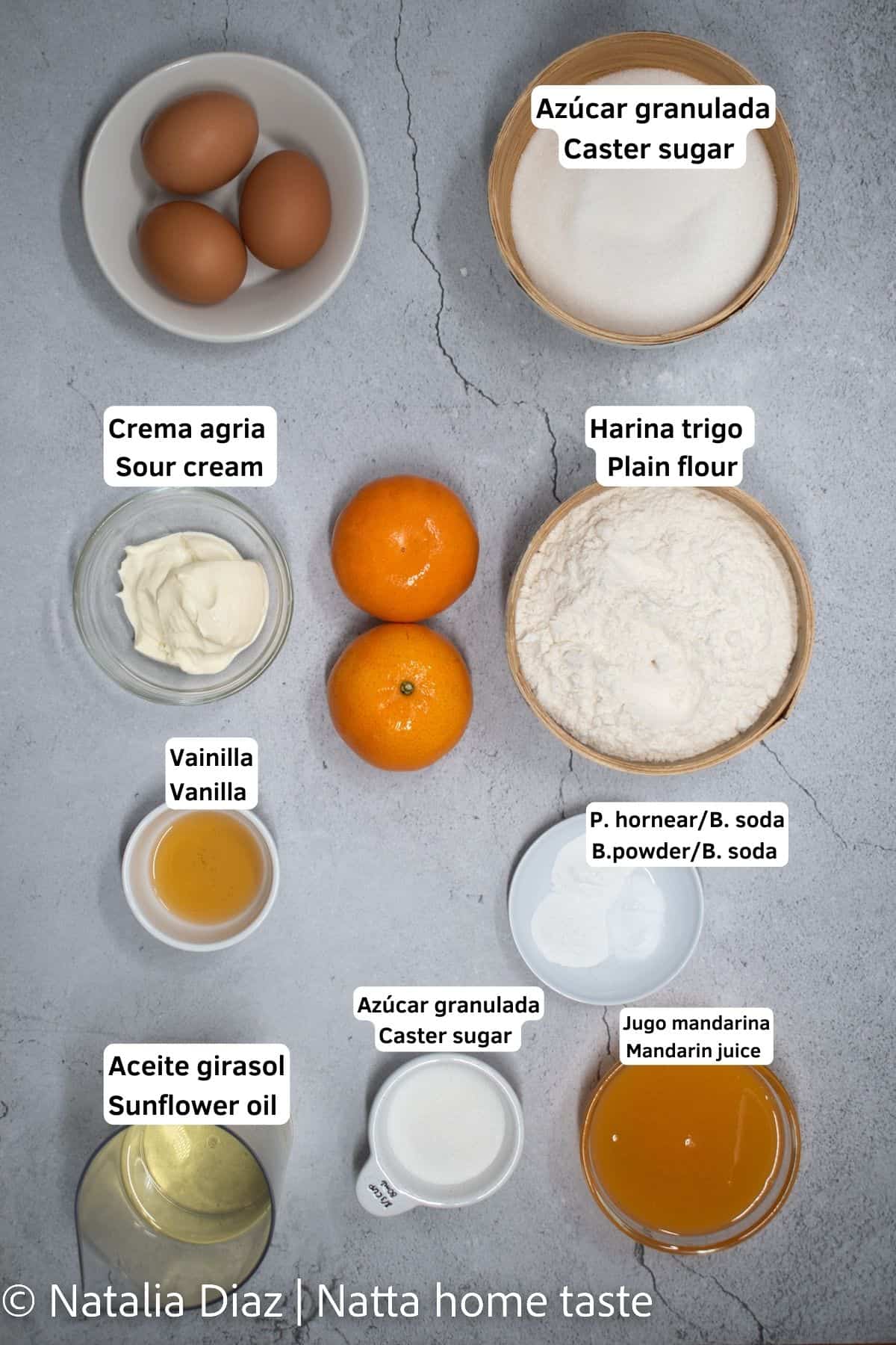 ingredientes para preparar un budín de mandarinas con cascaras. Azúcar, harina, huevos, crema agria, aceite de girasol. todos los ingredientes servidos en contenedores redondos.