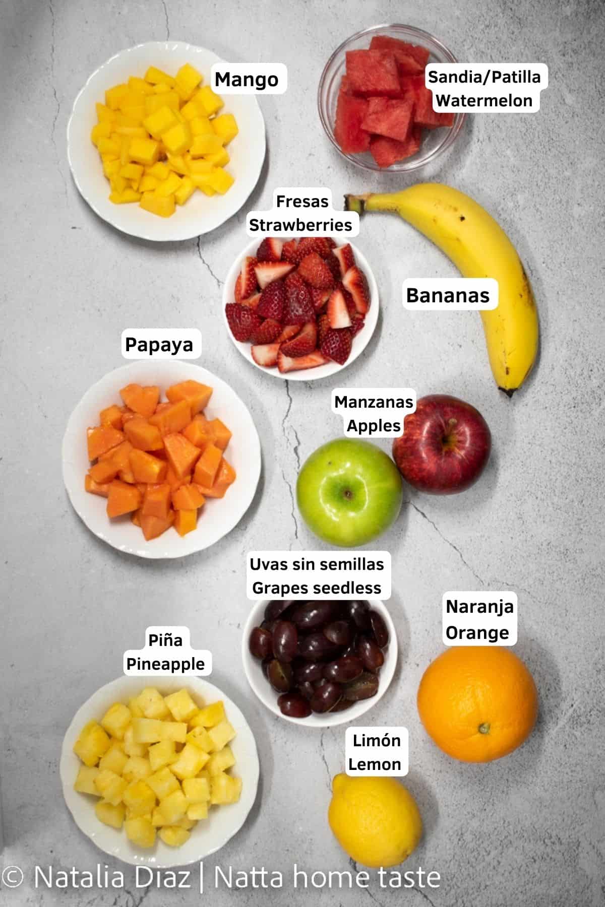 Ingredientes para preparar Salpicón de frutas colombiano. Mango, sandia, fresas, papaya, manzanas, bananas, uvas, naranjas, limón. todos los ingredientes están cortados en trozos pequeños y servidos en contenedores pequeños redondos.