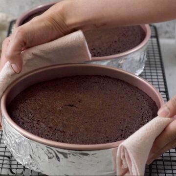 molde redondo con un pastel de chocolate sobre rejilla acabado de salir del horno.