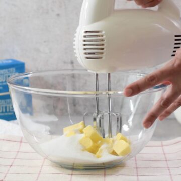 tazón transparente con mantequilla y azúcar con una batidora de mano