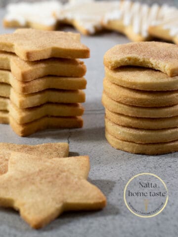 galletas de mantequilla en forma de estrellas y círculos una sobre otra sobre una mesa.