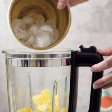 vaso de vidrio de una licuadora con trozos de piña y hielo 