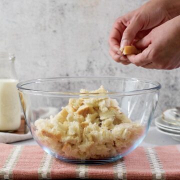 pan blanco en un bol grande y transparente cortado en pedazos pequeños con las manos.