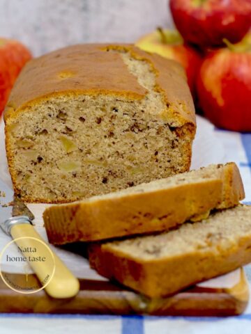 bizcocho de manzana sobre una tabla con manzanas rojas atrás