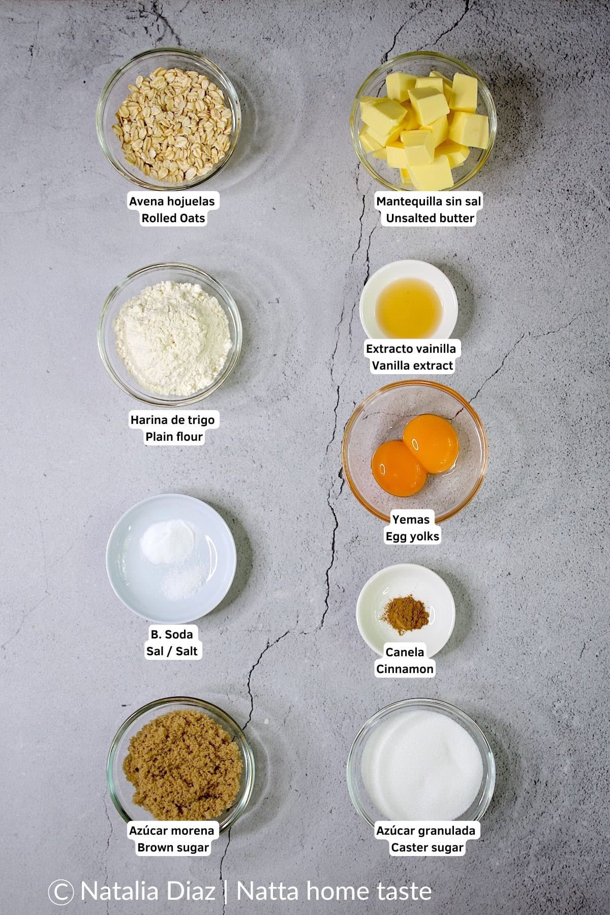 Ingredientes para preparar galletas de avena. Todos los ingredientes están en pequeños contenedores redondos. Copos de avena, mantequilla, harina, vainilla, yemas de huevo, canela y azúcar. 