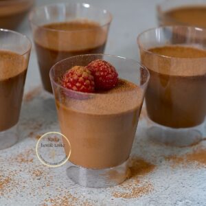 mousse de chocolate sin azúcar en vasitos transparente sobre una mesa gris con frambuesas encima