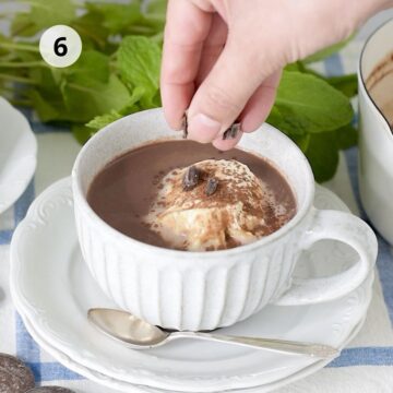 bebida con crema batida y trozos de chocolate sobre un plato blanco redondo