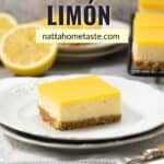 cheesecake de limón partido en una porción cuadrada sobre un plato blanco redondo con medio limón en la parte de atrás