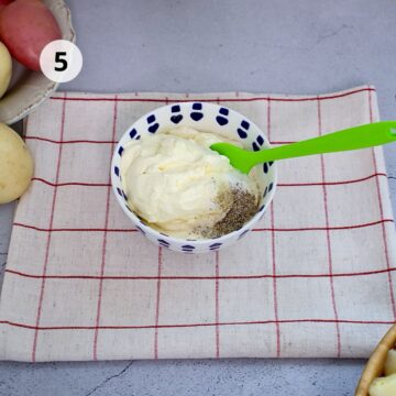 bol blanco con mayonesa, crema agria, sal y pimienta y una espátula de silicona verde.