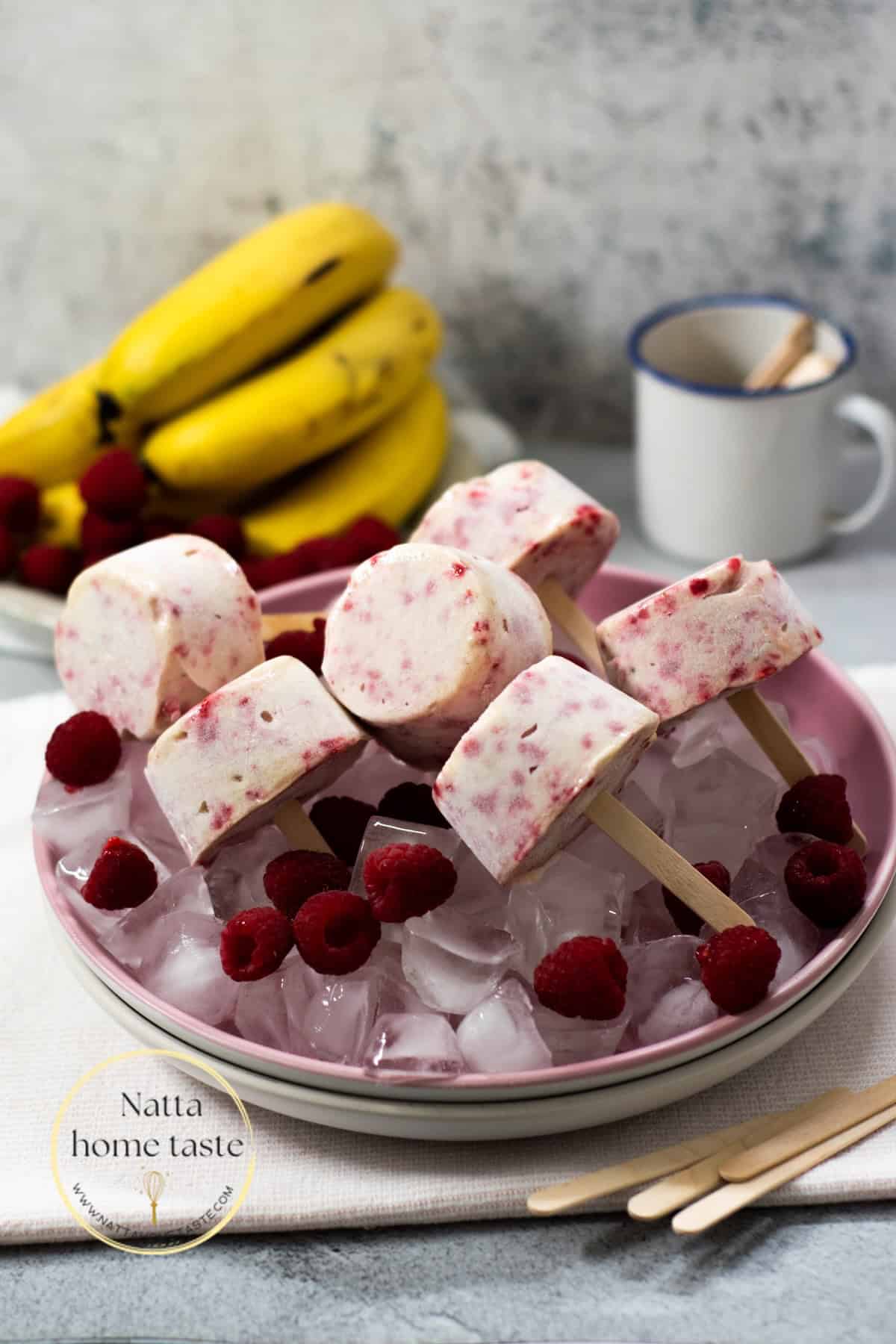 helado de banana en forma de paleta sobre un plato con hielo. Algunos bananos frescos sen la parte de atrás.