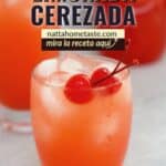 limonada cereza en un vaso de vidrio con hielo y dos cerezas en almíbar.