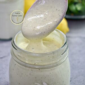vinagreta de yogur en un contenedor de vidrio con una cuchara