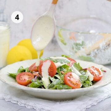 ensalada de lechugas y tomates sobre un plato redondo con un aderezo cremoso.