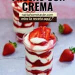 Dos vasos de fresas con crema en capas, decorados con fresas frescas y servidos en una mesa con fondo rosa. Un postre cremoso y delicioso, ideal para vender o disfrutar en casa.