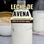 leche de avena casera en un frasco de vidrio sobre una mesa con una taza de avena en copos en la parte de atrás.
