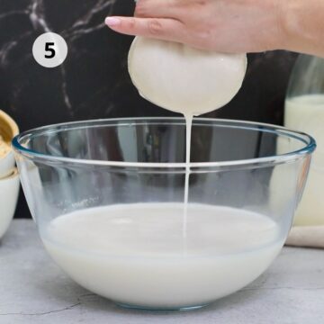 imagen de frente de un tazón grande con leche de avena recién exprimida con un paño para quesos 