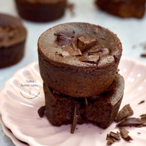Brownies sin huevo caseros, servidos en un plato rosa. Están hechos con frijoles negros y avena, y decorados con trozos de chocolate derretido. Uno de los brownies está partido, mostrando su interior húmedo y chocolatoso.