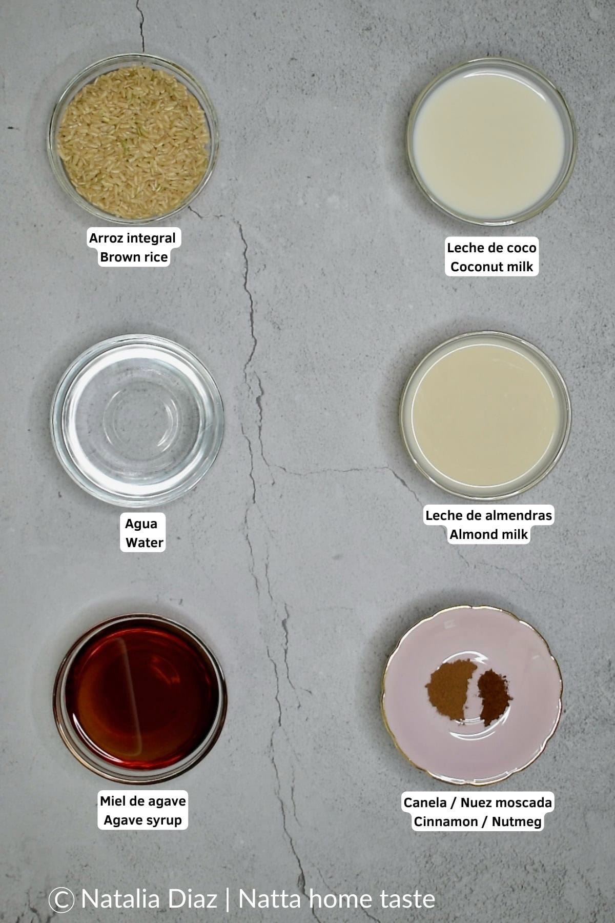 Seis pequeños tazones con los ingredientes alineados en una superficie gris. De arriba a abajo: arroz integral, leche de coco, agua, leche de almendras, miel de agave y una mezcla de canela y nuez moscada.