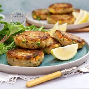 Tortitas de atún con papa doradas por fuera y suaves por dentro, servidas con gajos de limón y hojas verdes.