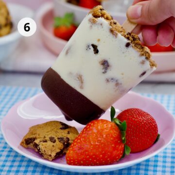 Paleta casera de leche con galletas y chocolate, servida sobre un plato rosa con fresas frescas y una galleta partida.