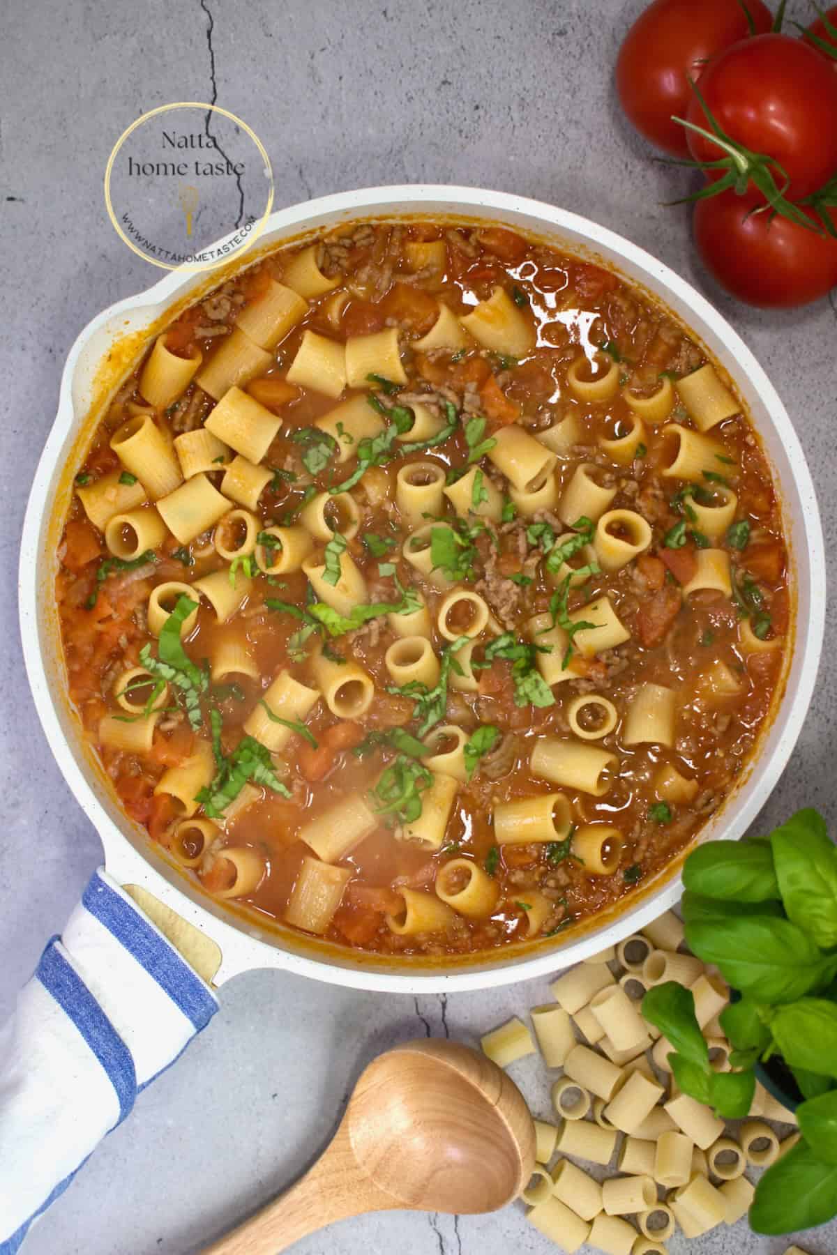 pasta corta en salsa de tomate con albahaca, vista superior en sartén blanco; cena rápida one-pot.