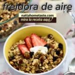 Gráfico vertical: tazón blanco con granola casera hecha en freidora de aire, servida con fresas y yogur; jarra de leche detrás y texto “GRANOLA EN freidora de aire – nattahometaste.com, mira la receta aquí