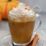 Pumpkin Spice Latte casero servido en taza de vidrio con crema batida y canela espolvoreada, una bebida de café con calabaza y especias perfecta para el otoño.