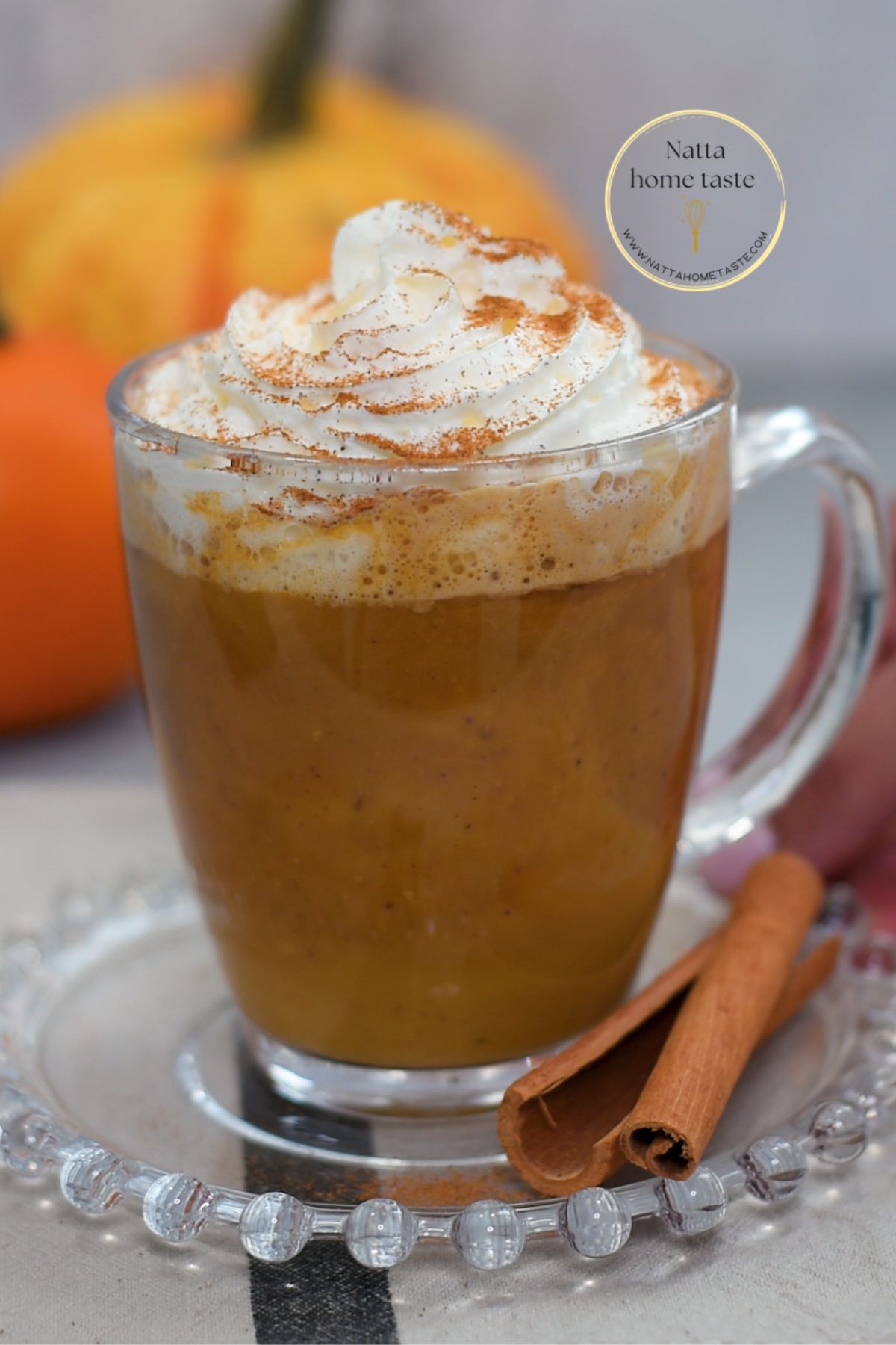 Pumpkin Spice Latte casero servido en taza de vidrio con crema batida y canela espolvoreada, una bebida de café con calabaza y especias perfecta para el otoño.