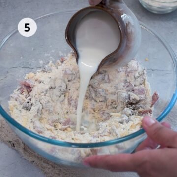 Persona vertiendo la mezcla de leche en el tazón con los ingredientes secos y adicionales para formar la masa.