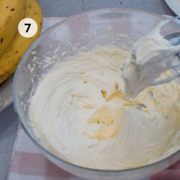 Crema de mantequilla recién batida con textura suave y cremosa dentro de un tazón de vidrio. Lista para extender sobre in bizcocho.