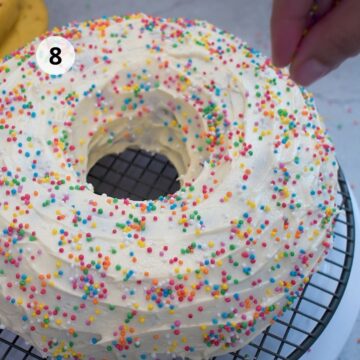 Bizcocho cubierto con crema de mantequilla blanca y decorado con grageas de colores.