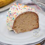 Rebanada de torta de cumpleaños de banana con crema de mantequilla y grageas de colores, mostrando su miga húmeda y suave.