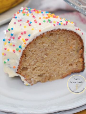 Rebanada de torta de cumpleaños de banana con crema de mantequilla y grageas de colores, mostrando su miga húmeda y suave.