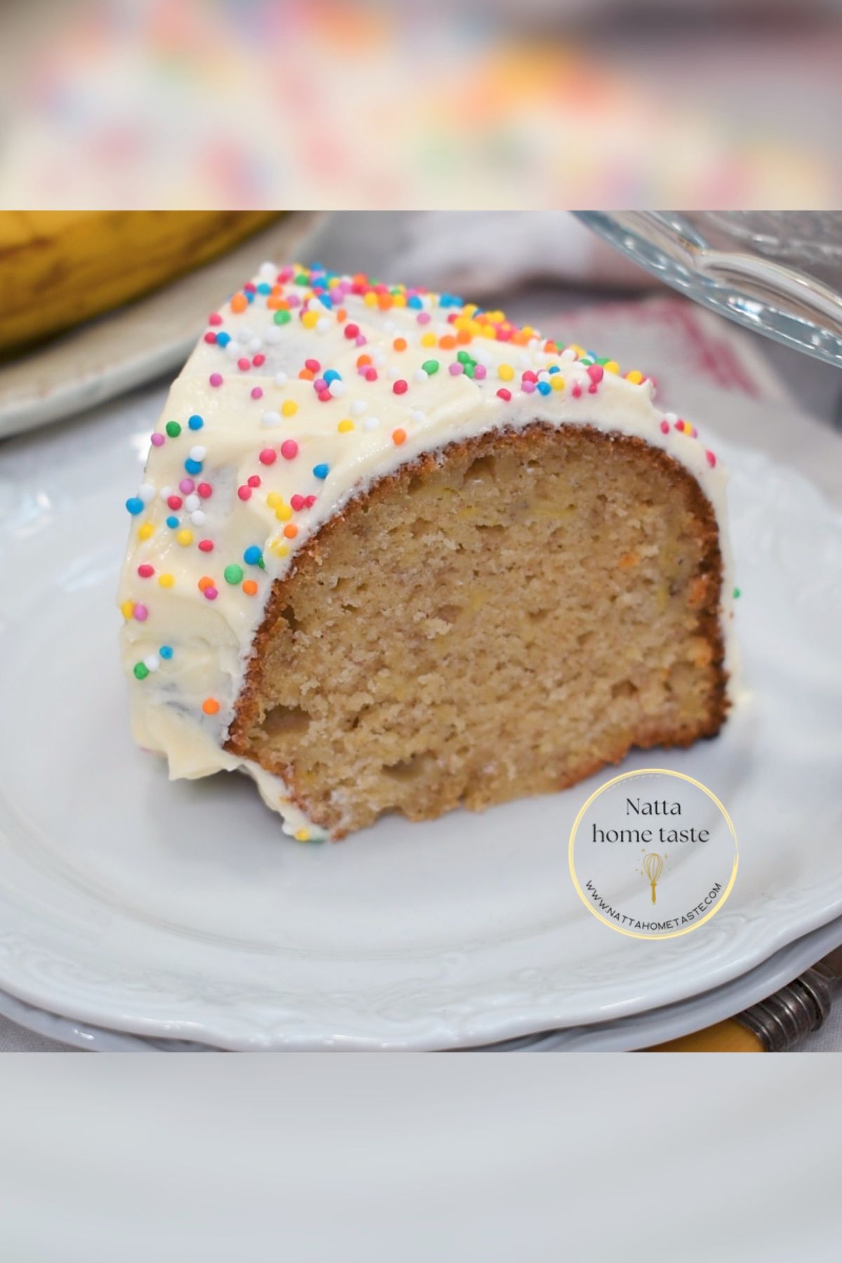 Rebanada de torta de cumpleaños de banana con crema de mantequilla y grageas de colores, mostrando su miga húmeda y suave.