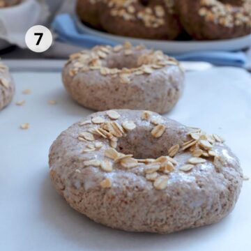 Panes en forma de aro pincelados y decorados con hojuelas de avena.