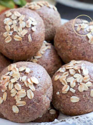 Rollitos de pan de avena sin huevo recién horneados y decorados con hojuelas de avena.