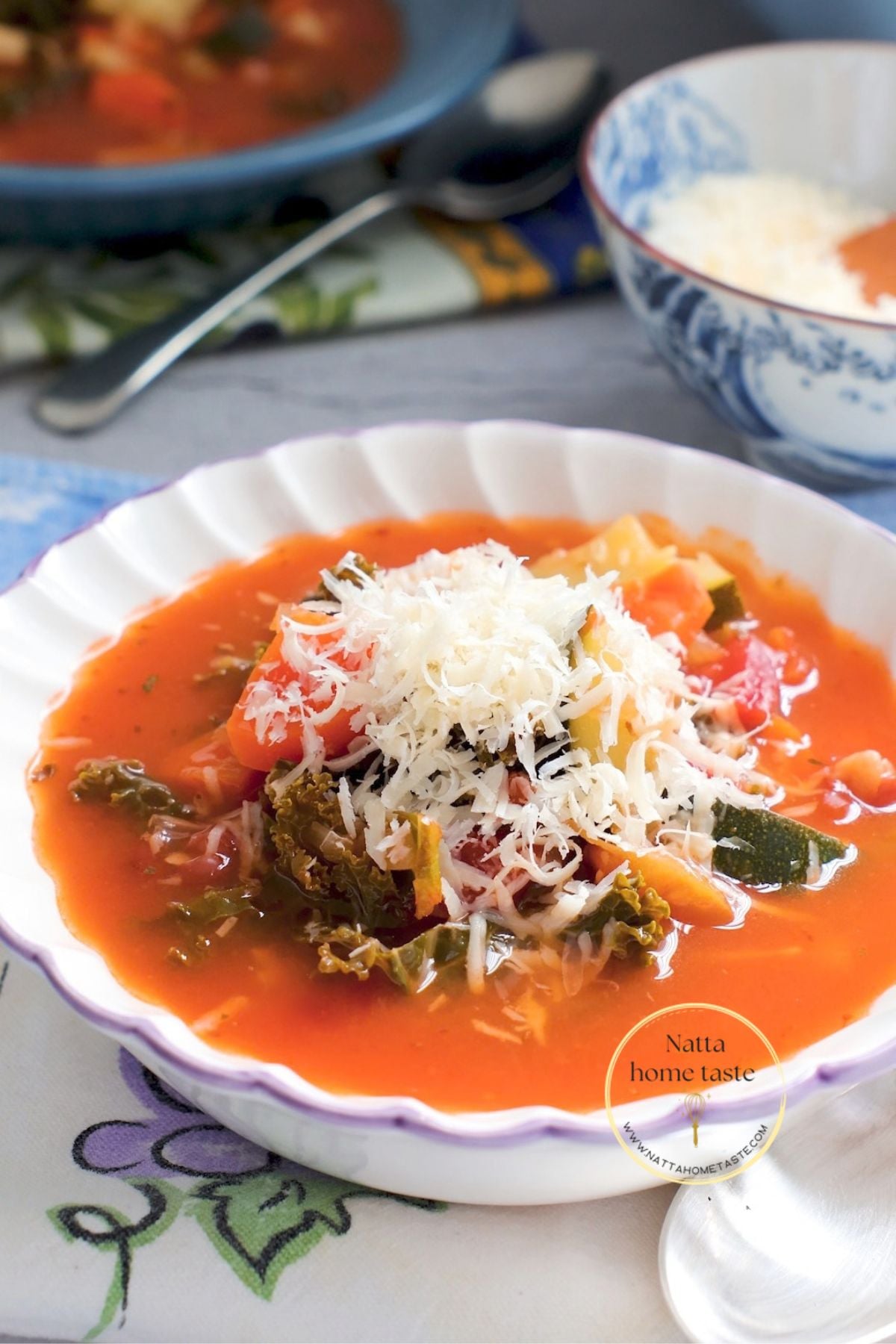 Sopa minestrone vegetariana con pasta, frijoles, calabacín y kale, servida con queso parmesano rallado.
