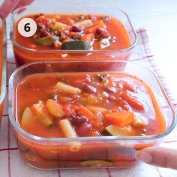 Sopa de verduras con pasta y frijoles distribuida en recipientes de vidrio para refrigerar.
