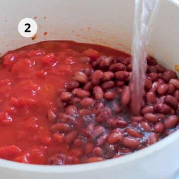 Tomates en trozos, frijoles rojos y agua añadidos a una olla.