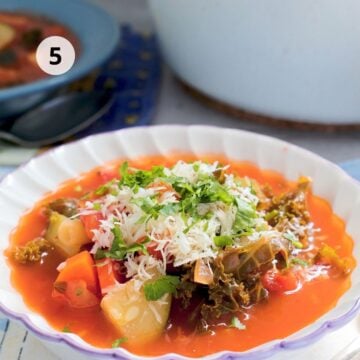 Plato de sopa de verduras con pasta, frijoles, kale, perejil y queso rallado.