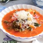Sopa minestrone vegetariana con pasta, frijoles, calabacín y kale, servida con queso parmesano rallado.